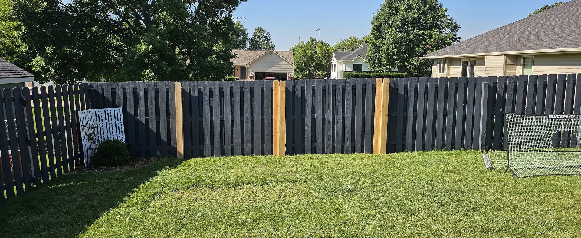 Backyard with green lawn, black fence, and a soccer goal under sunny skies
