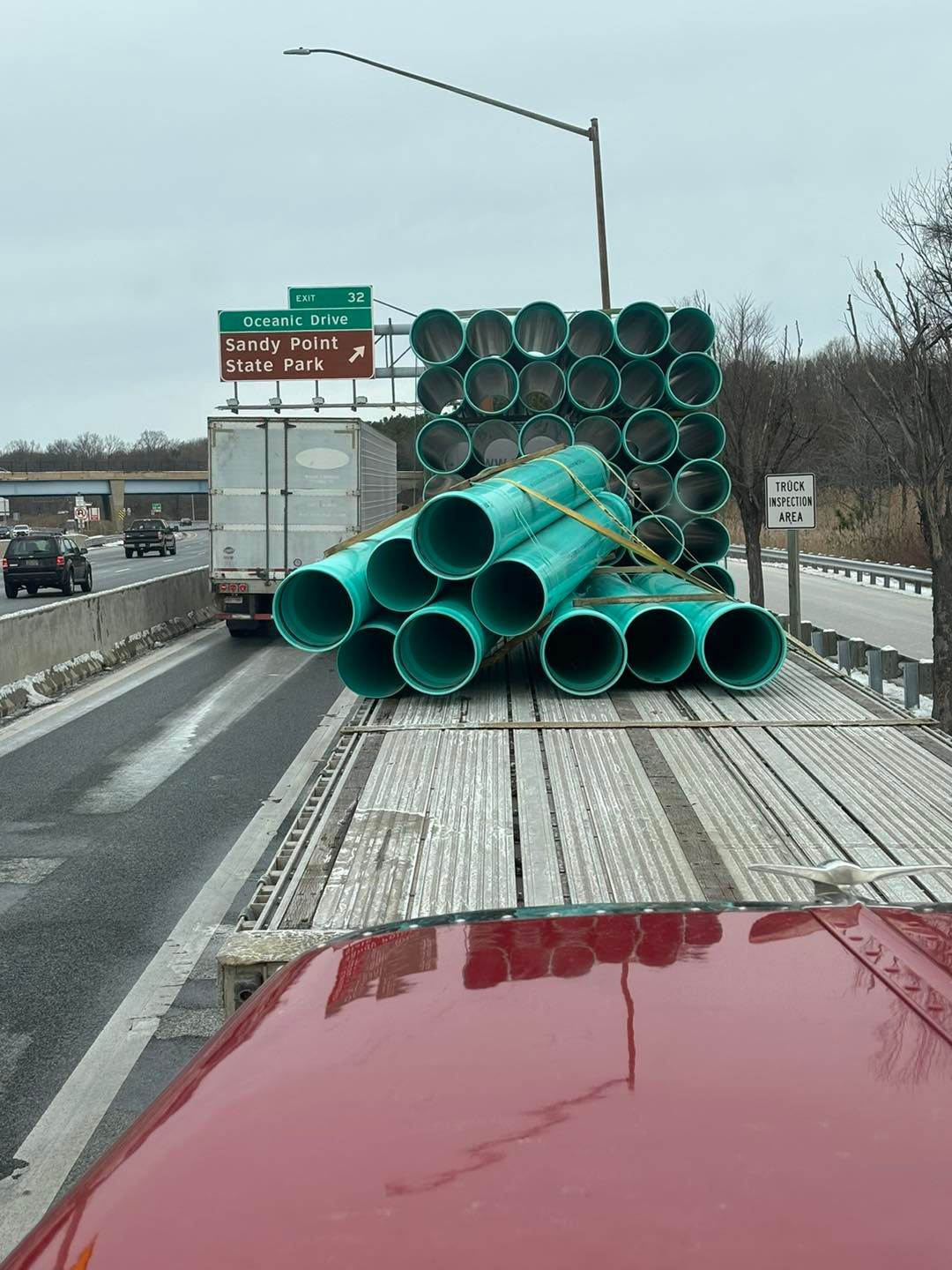 A truck is carrying a load of green pipes on the back of it