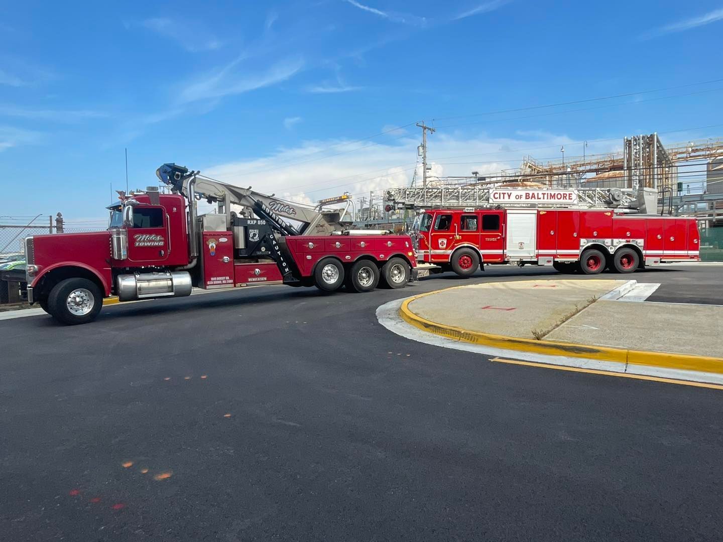 a red tow truck and a red fire truck are parked on the side of the road .