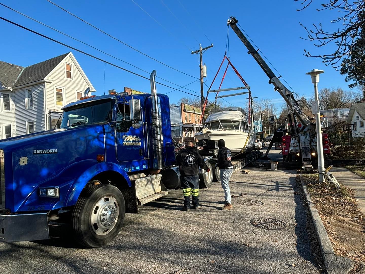 a blue truck is towing a boat down a street