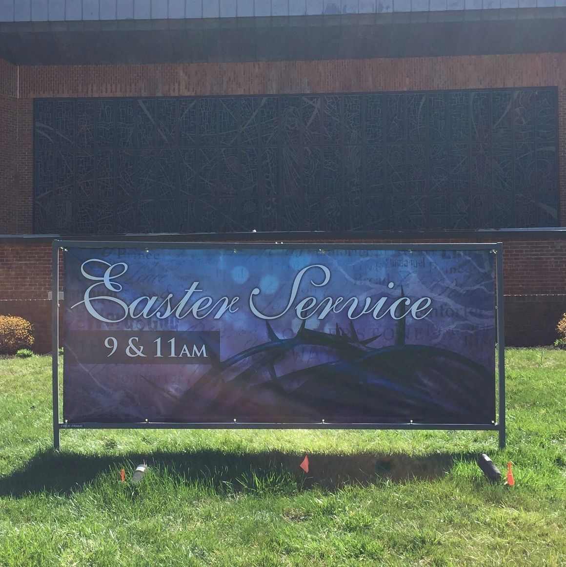 A banner on a lawn in front of a building announces an Easter service at 9 and 11 a.m.