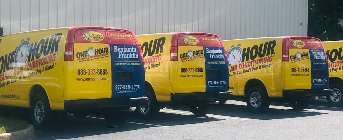 A row of bright yellow One Hour Heating & Air Conditioning service vans parked in a line outdoors.