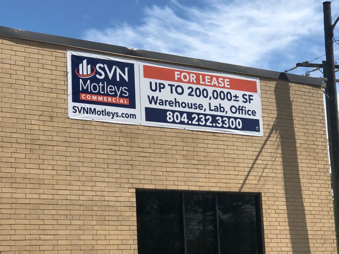 A tan brick building wall with a sign for lease, displaying 