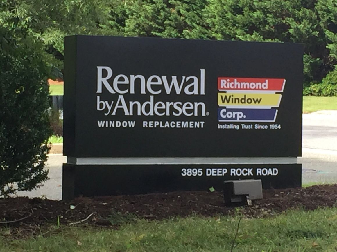 A sign for Renewal by Andersen and Richmond Window Corp. at 3895 Deep Rock Road surrounded by grass and trees.