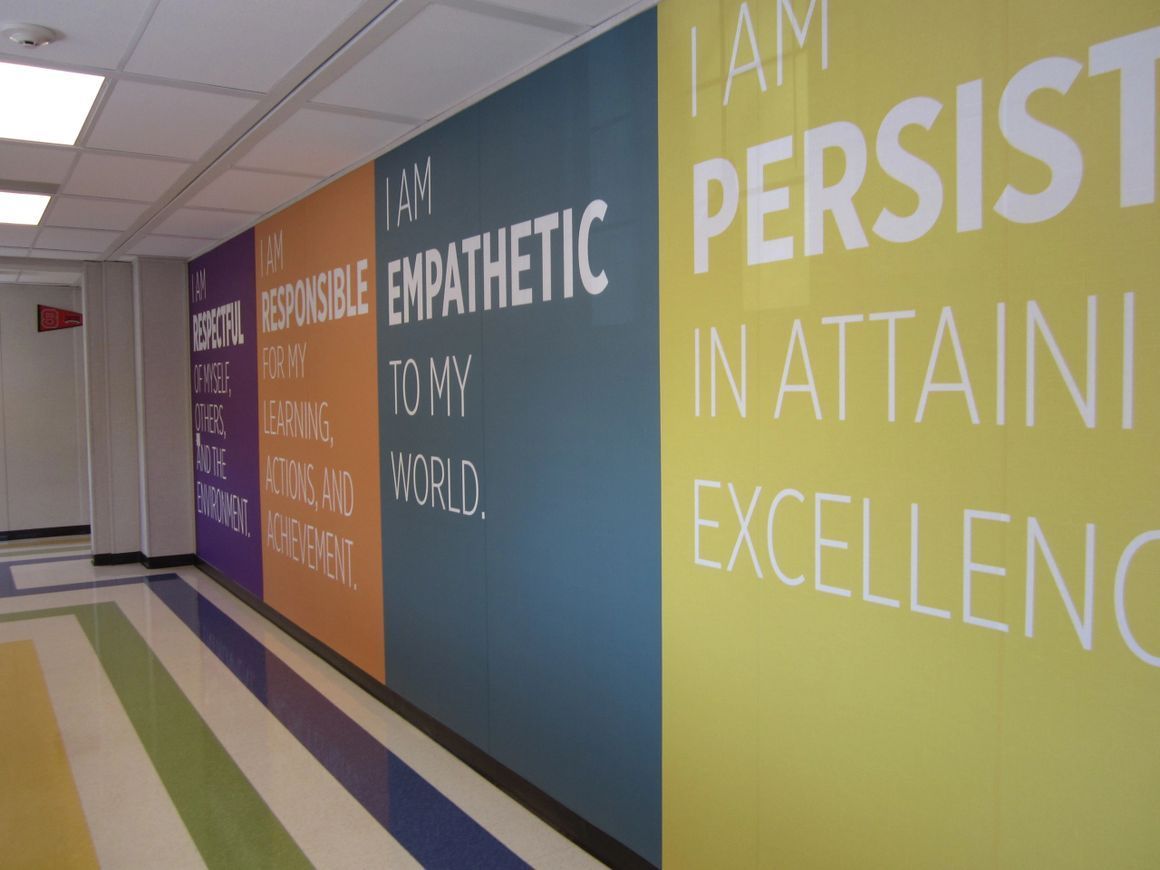 A hallway featuring wall panels with inspirational text in colors including yellow, blue, orange, and purple.
