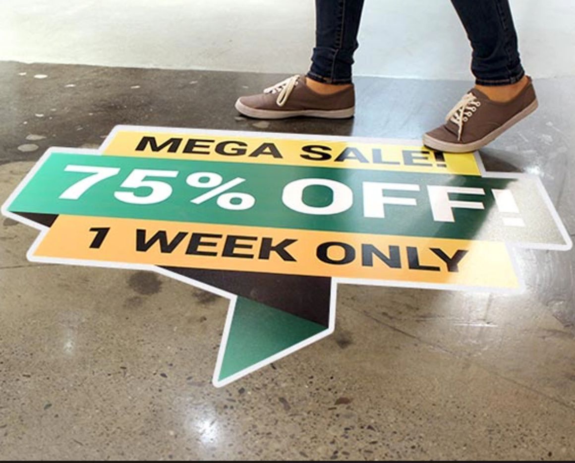 A person walks over a floor sticker that reads 