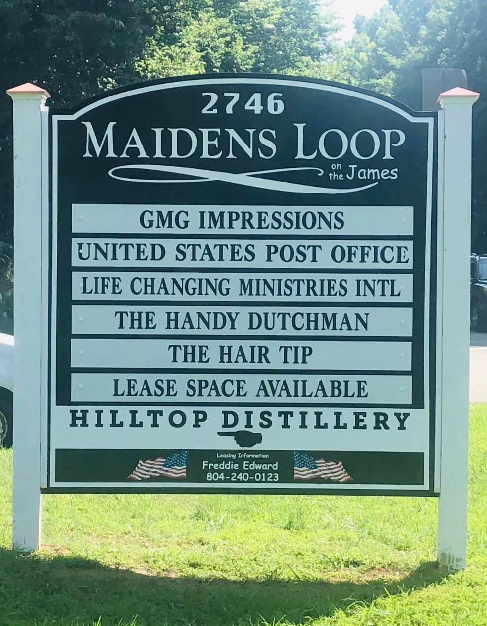 A roadside directory sign for 2746 Maidens Loop, listing various businesses including a post office and a distillery.