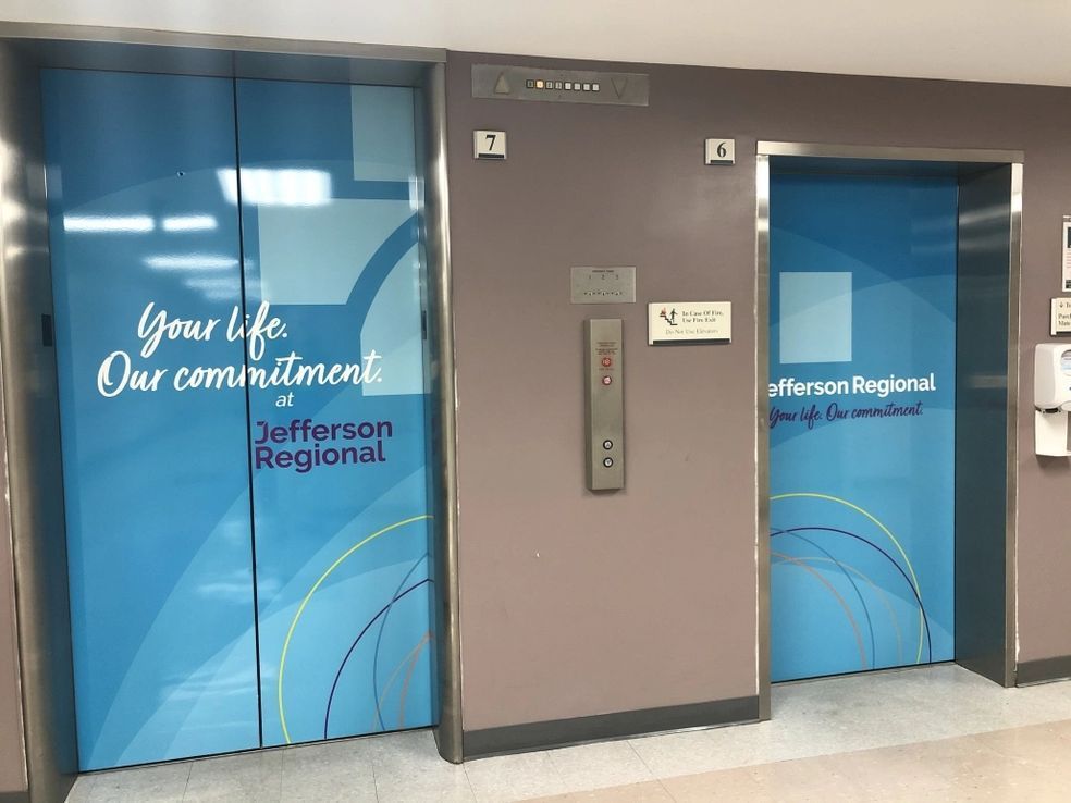 Two blue elevators at Jefferson Regional, featuring the slogan 
