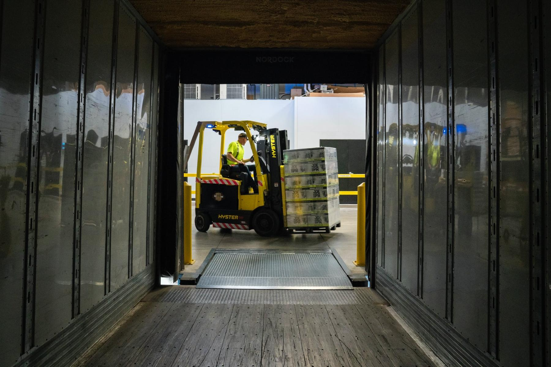 A forklift is loading boxes into a container in a warehouse.