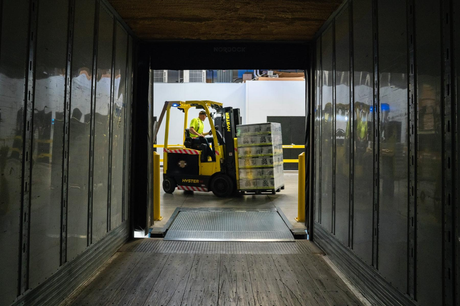A forklift is loading boxes into a container in a warehouse.