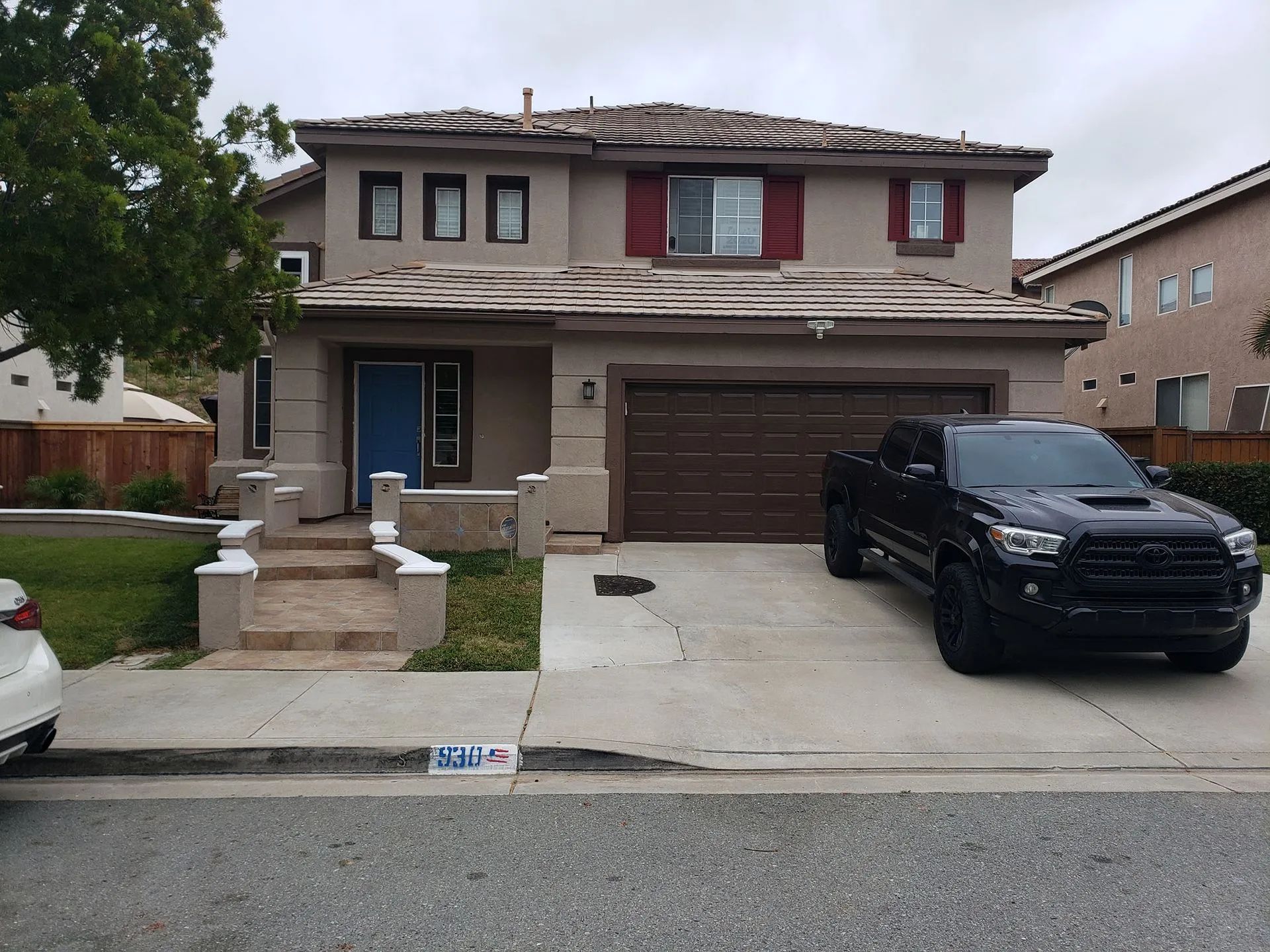 Suburban two-story house with a double garage and a black pickup truck parked in the driveway.