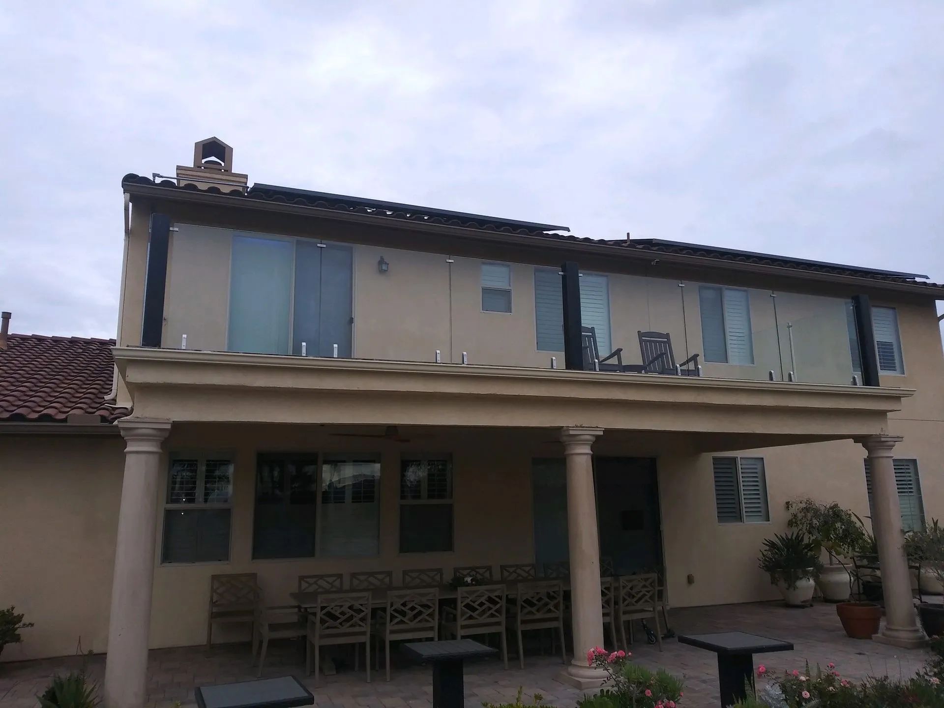 Two-story house with a covered porch, beige columns, and blue shutters under a cloudy sky