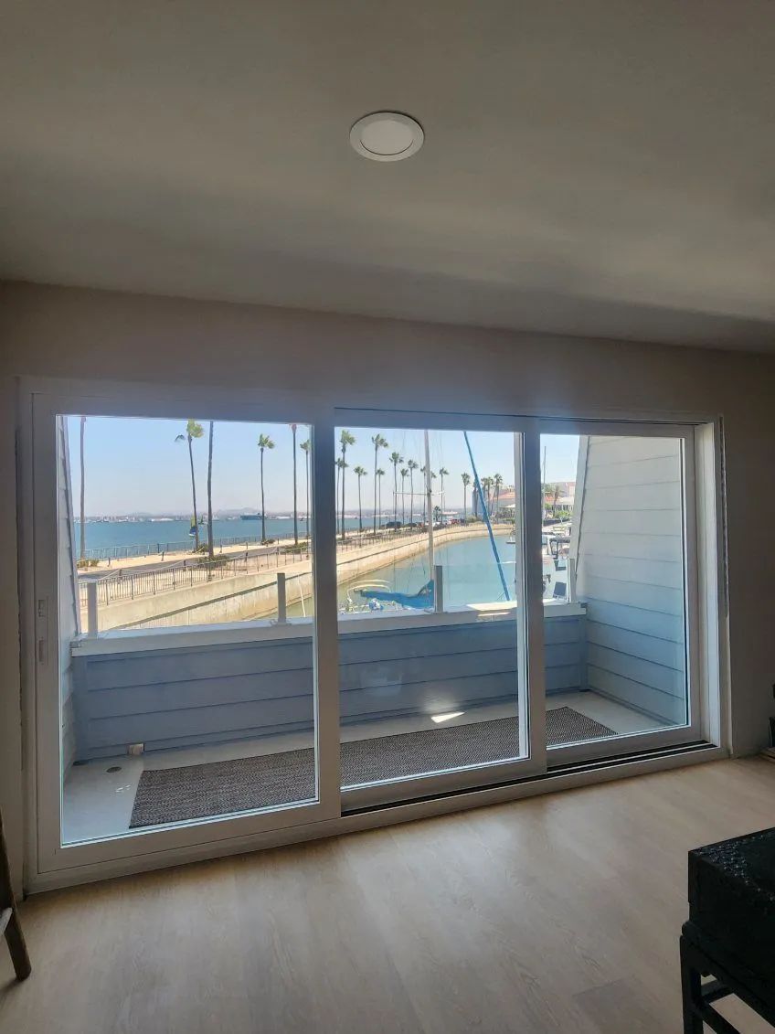 Empty room with sliding glass doors opening to a balcony and ocean view.