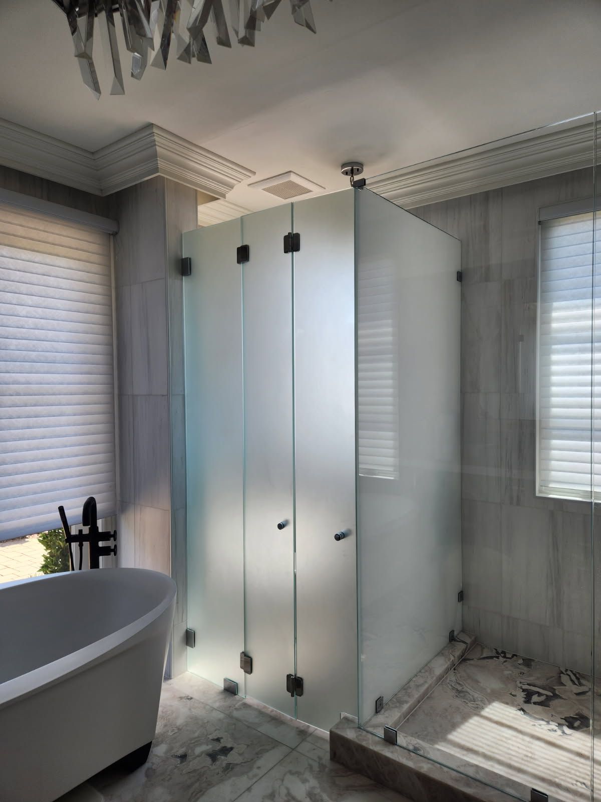 Modern bathroom with a glass shower stall, white bathtub, and tiled walls and floor