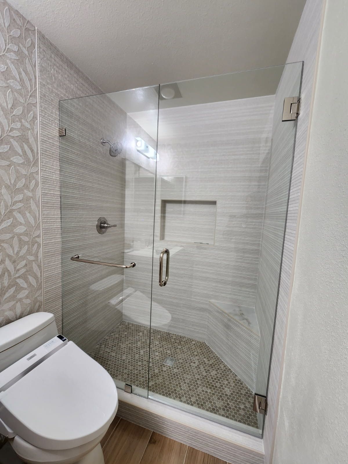 Small modern bathroom with a white toilet and a glass walk-in shower with tiled walls.