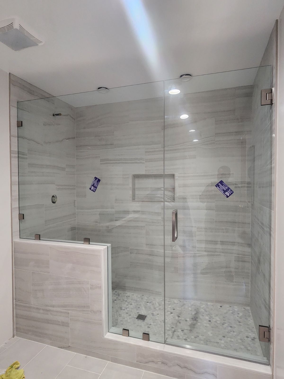 Modern tiled bathroom with glass-enclosed shower and pebble floor, viewed from the doorway