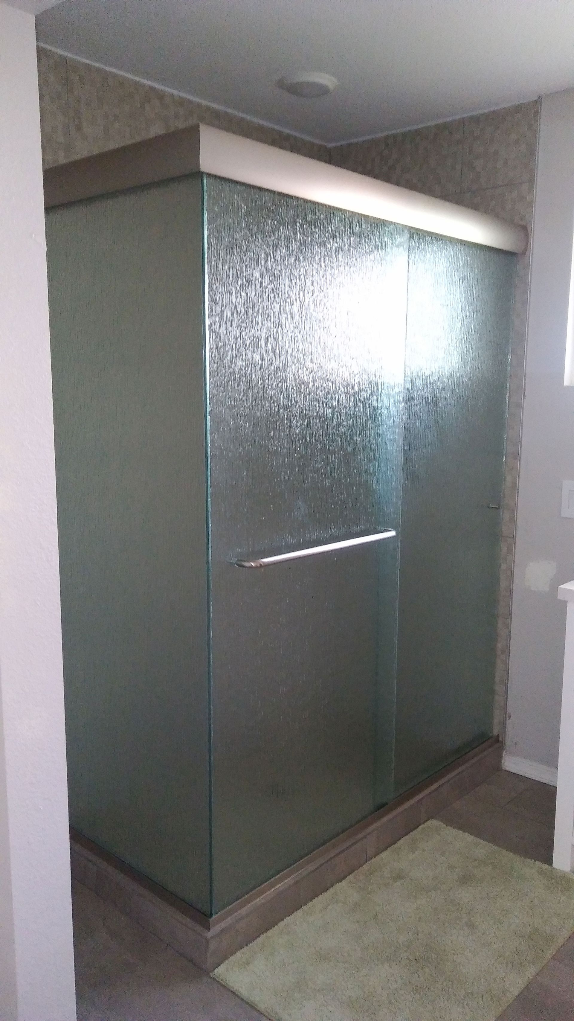 Frosted glass shower stall in a bathroom with tiled floor and beige walls