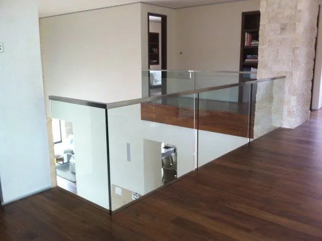 Modern interior with wood floor, glass railing, and stone accent wall overlooking a lower level