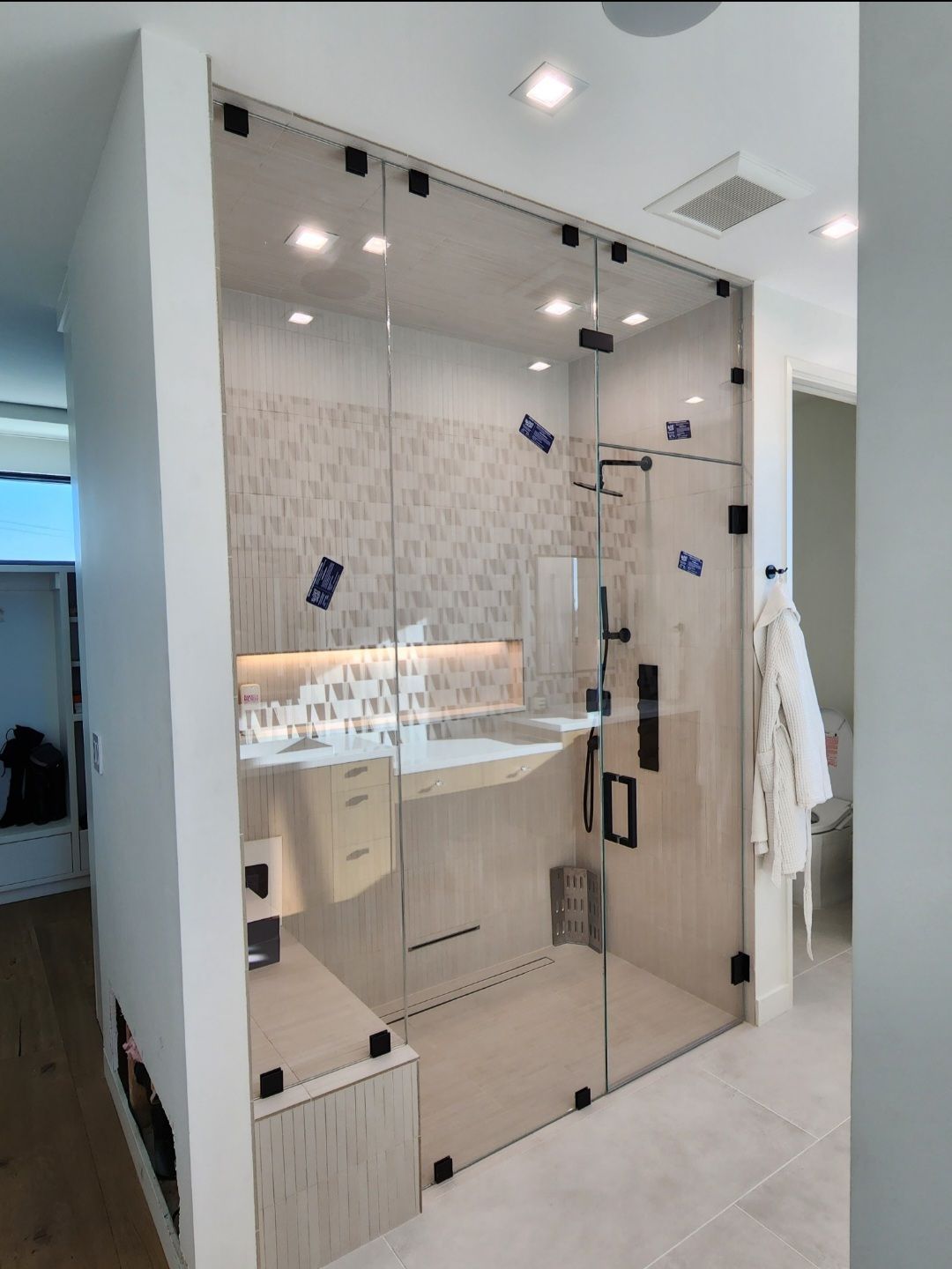 Modern bathroom with a glass-enclosed shower and vanity under bright ceiling lights