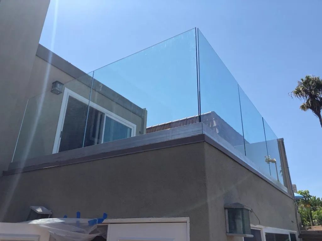 Modern house with rooftop glass railing under a clear blue sky