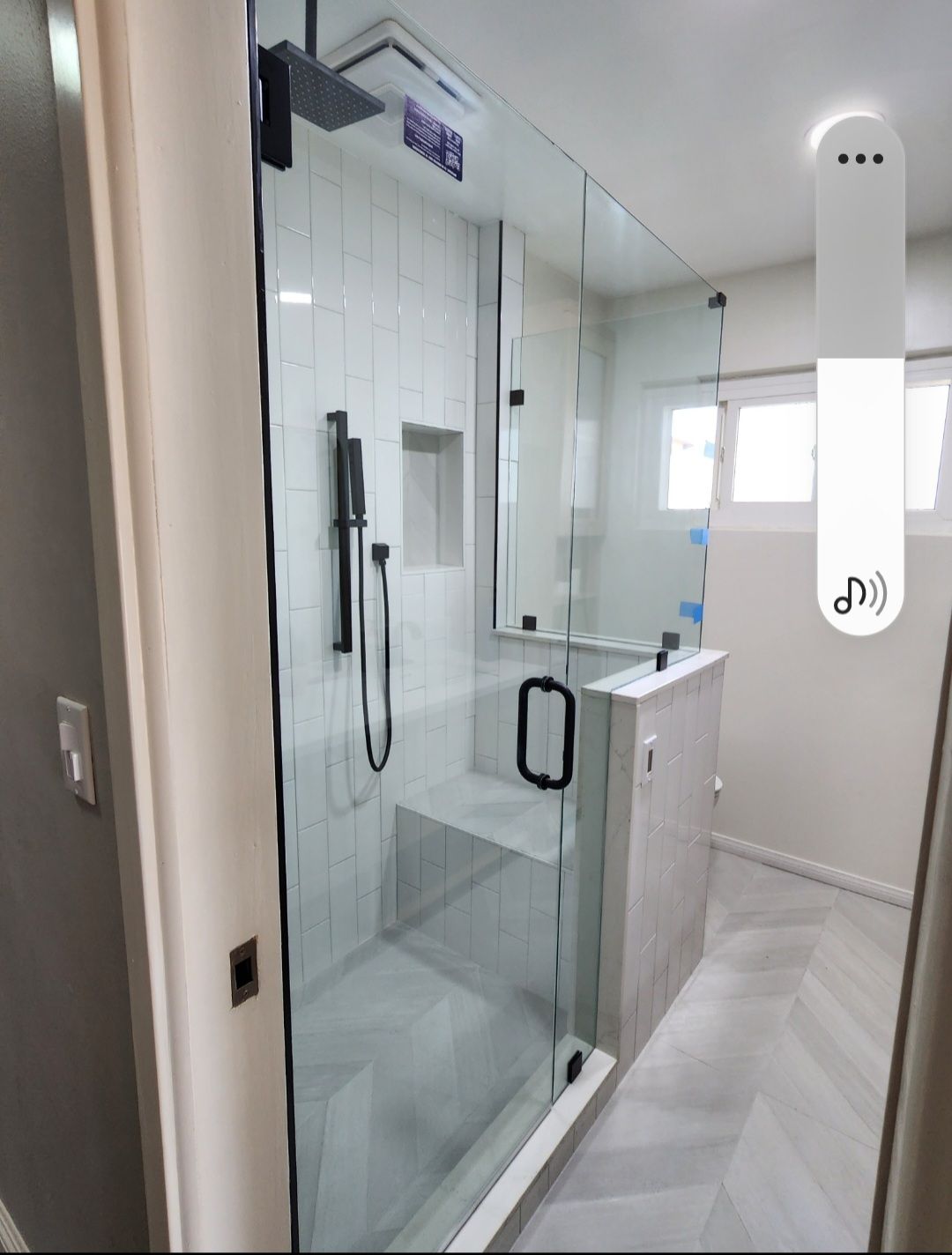 Modern bathroom with a glass shower enclosure, vanity sink, and white tiled floor.
