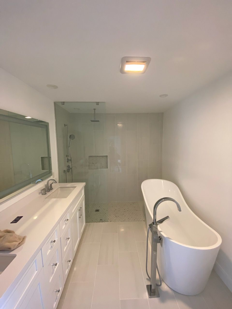 Modern white bathroom with double vanity, glass shower, and freestanding tub