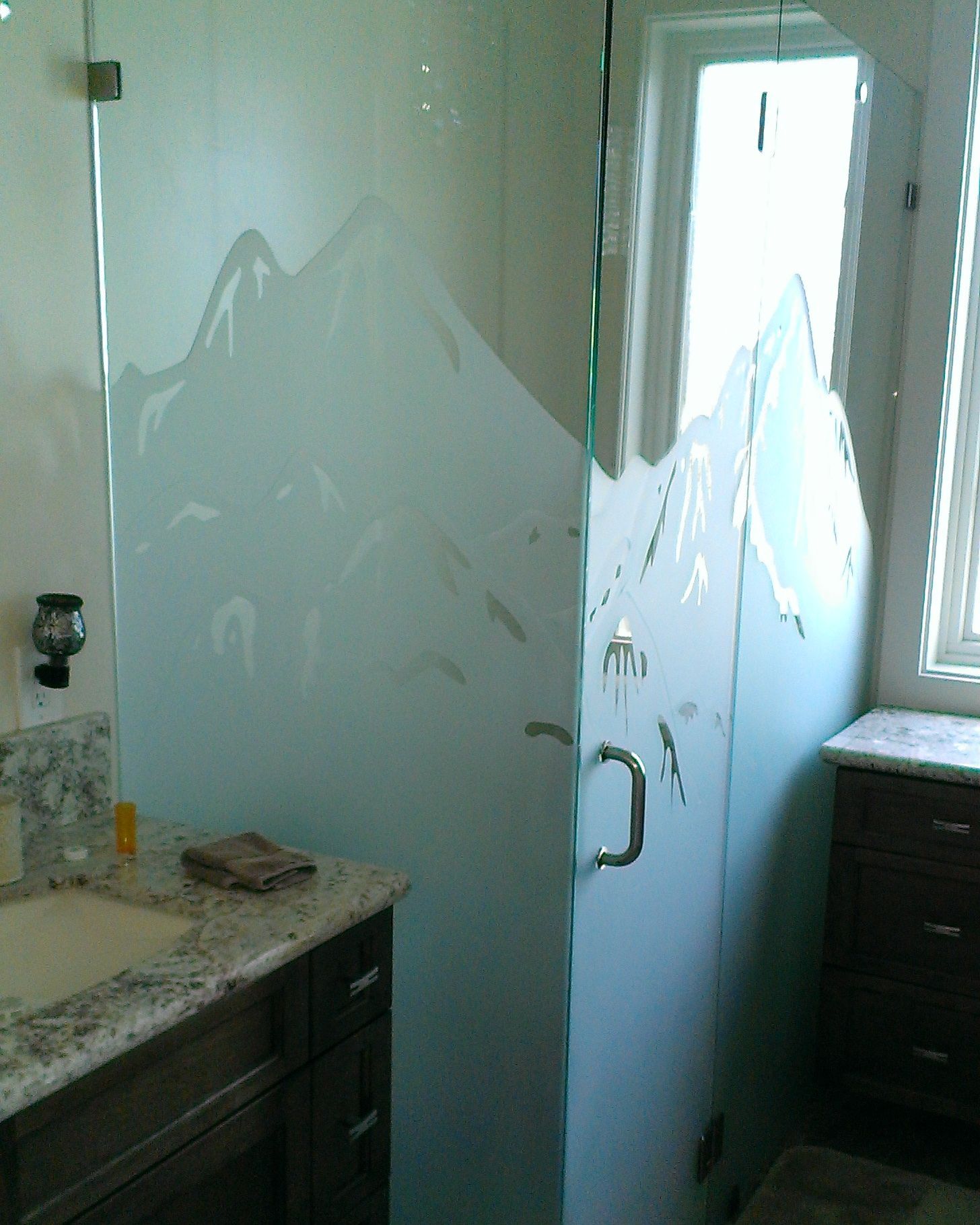 Bathroom with a glass shower door, dark vanity, and reflective wall art on the wall