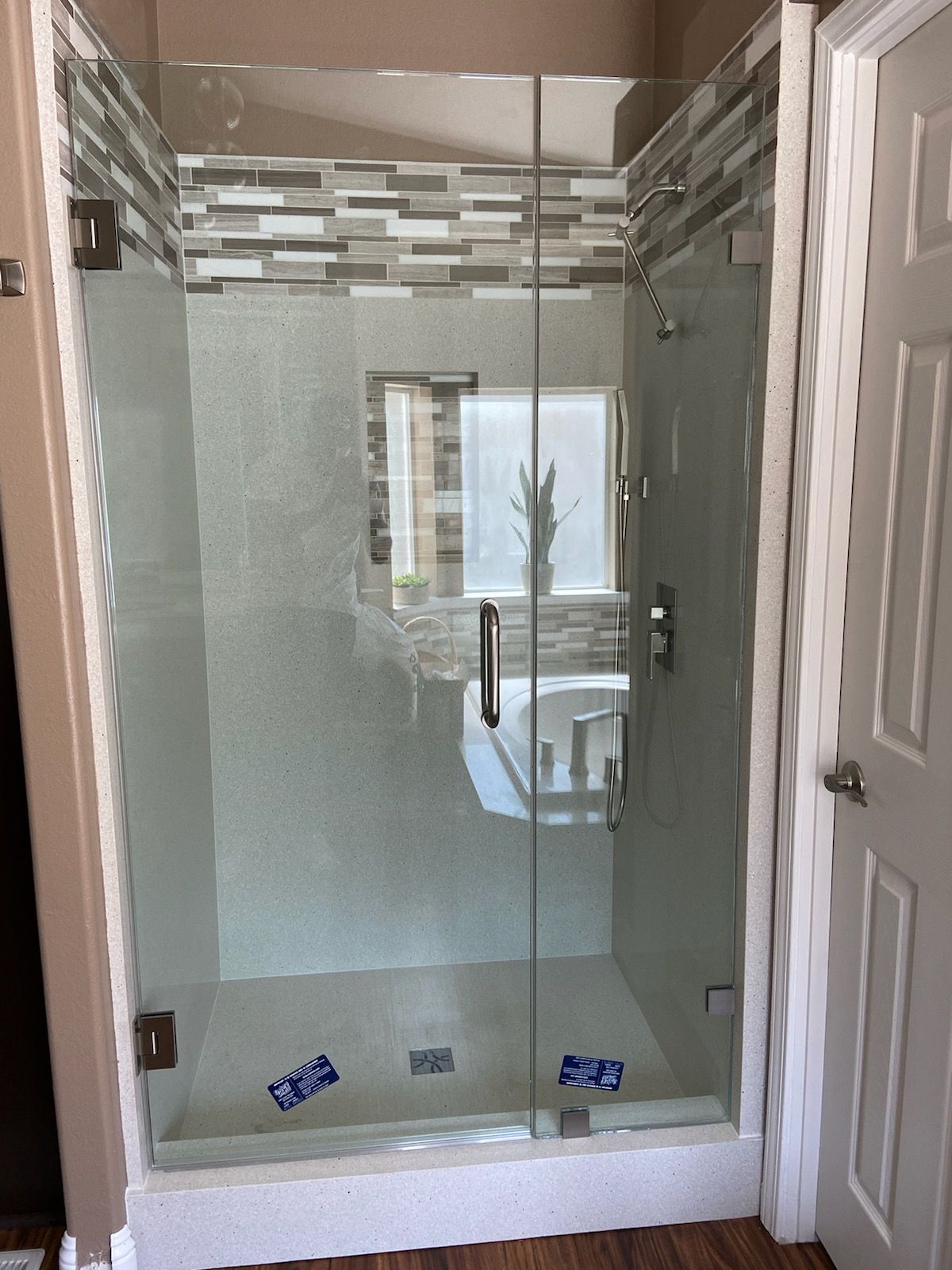Glass walk-in shower with white tile, frosted panels, and a tiled border above the door