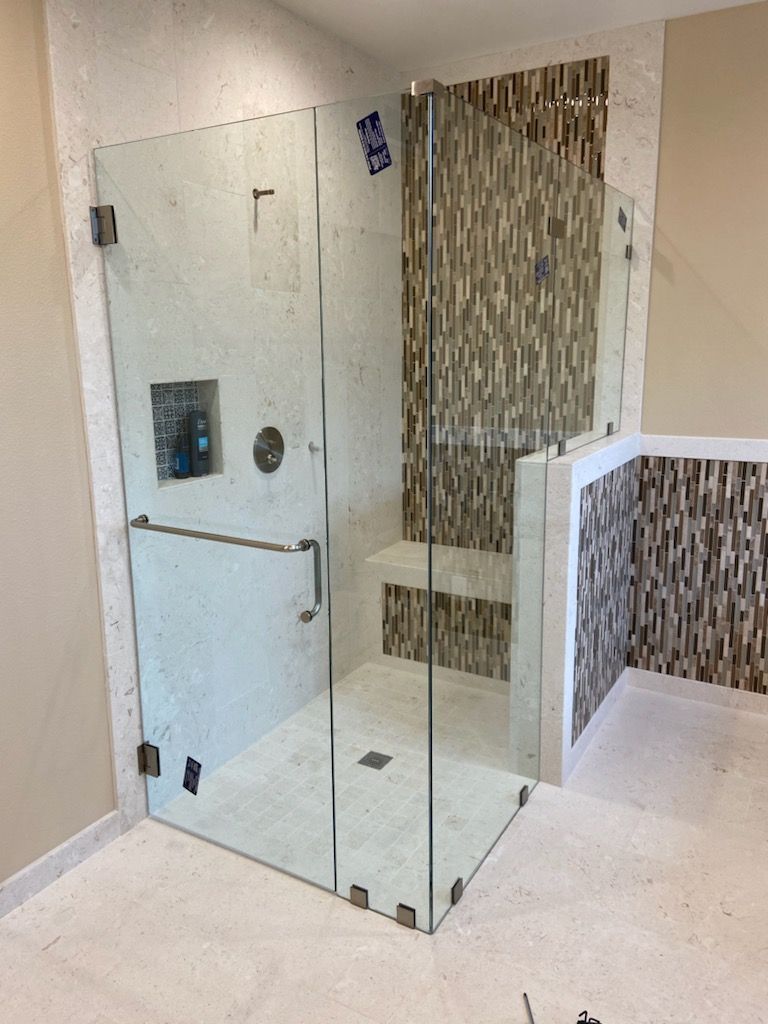 Glass shower enclosure with a tiled accent wall in a bathroom
