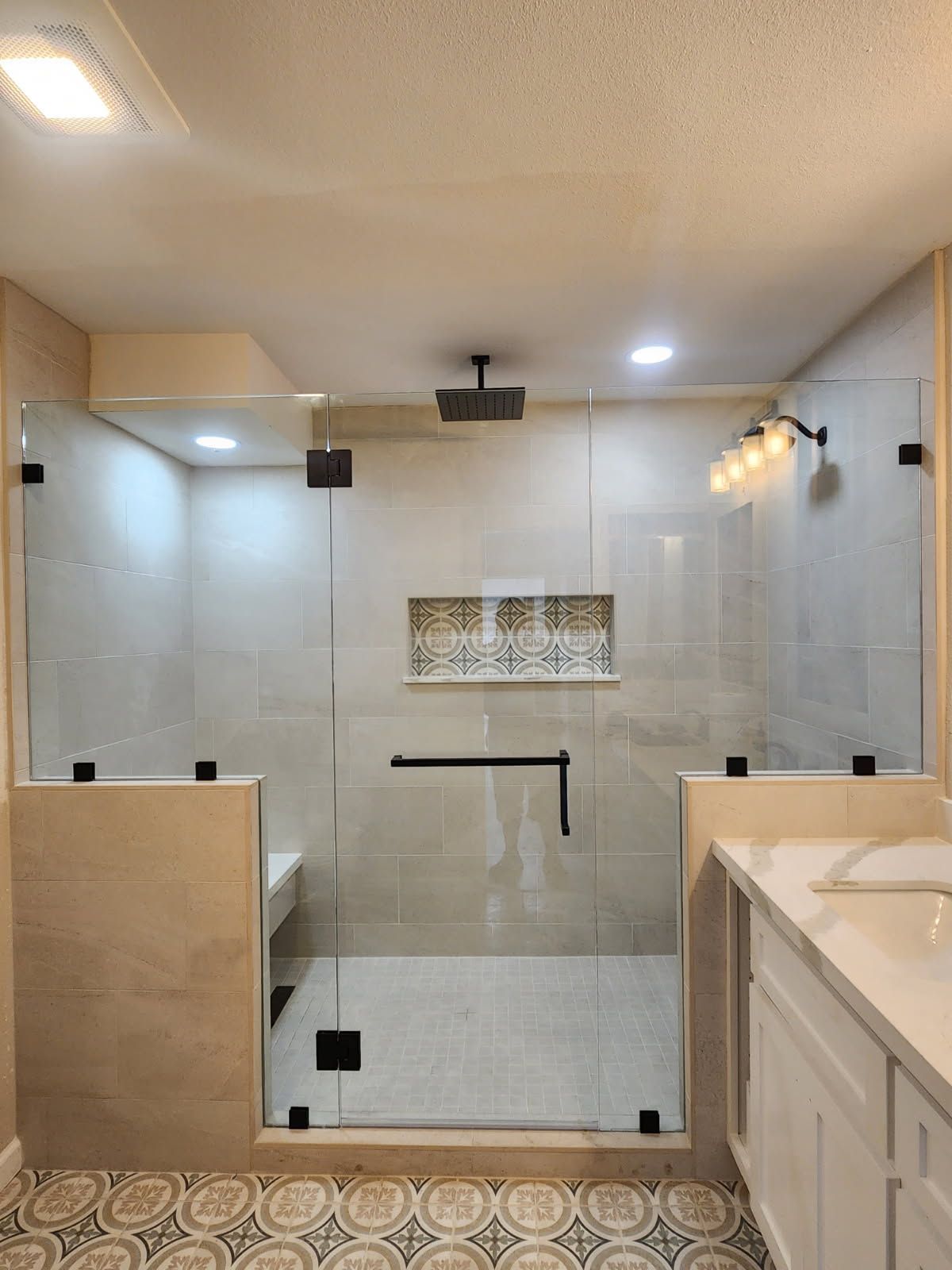 Modern bathroom with glass shower enclosure, beige tile, and white vanity.
