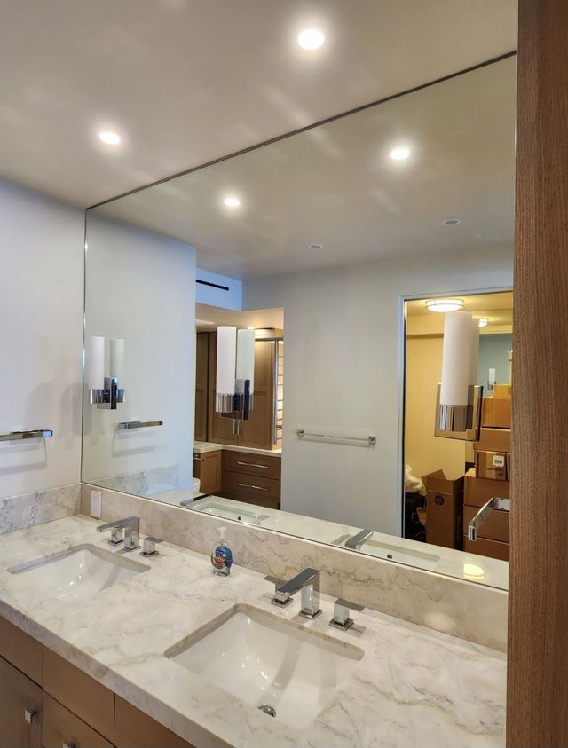 Modern bathroom with double vanity, large mirror, and white marble countertop under recessed lights