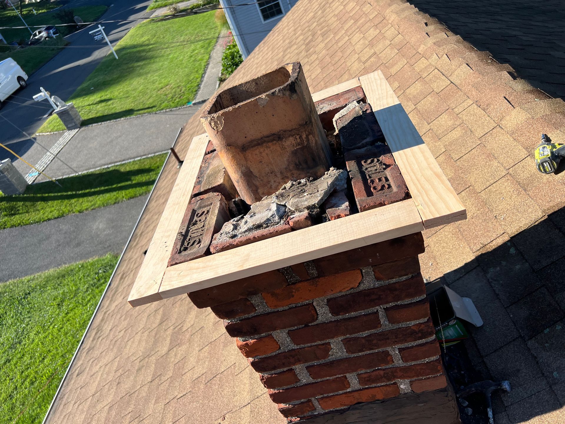 An overhead view of a residential brick chimney under repair, featuring a new wood frame surrounding the central flue.