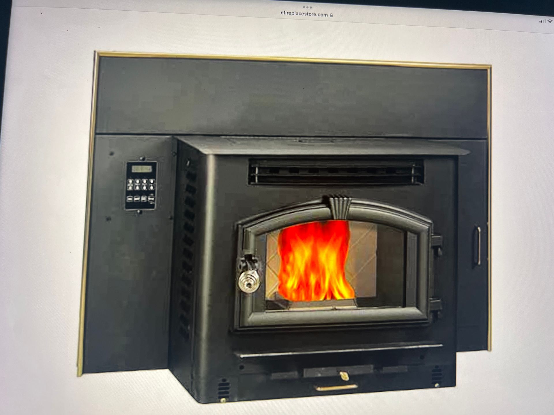 Black pellet stove fireplace insert with a gold-trimmed shroud, digital control panel, and visible fire in the glass.
