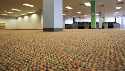 Large empty office space with patterned carpet and support columns.
