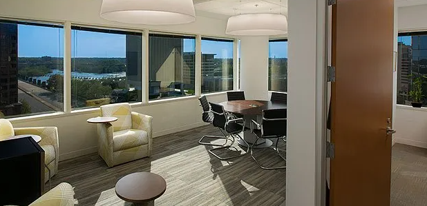 Interior office with a meeting table and chairs by a large window overlooking a city.