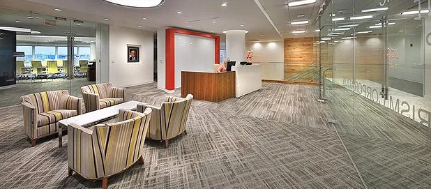Office reception area with seating, reception desk, and glass walls.