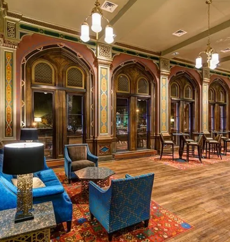Elegant hotel lobby with arched doorways, ornate trim, and blue furniture.