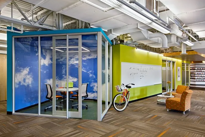 Modern office space with a meeting room featuring sky mural, white board, and bicycle.