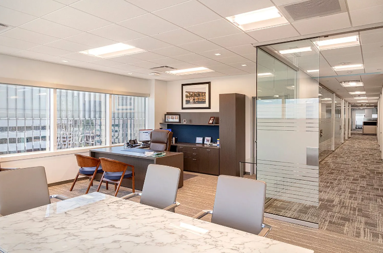 Office interior with a desk, conference table, and frosted glass walls.