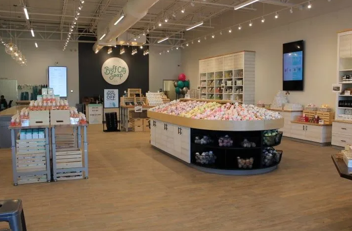 Interior of a brightly lit store with product displays and open space. Displays feature soaps and products.