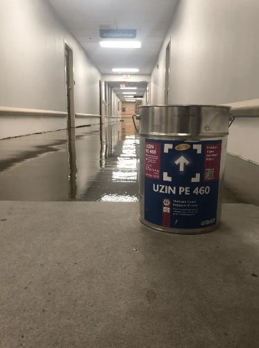 A flooded hallway with a bucket of Uzin PE 460 flooring product.