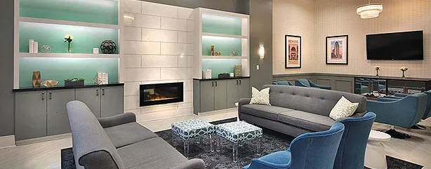 Modern living room with blue sofas, fireplace, and built-in shelving with decorative items.