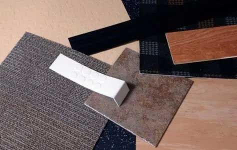 Samples of flooring materials: carpet, tile, and wood in various colors arranged on a surface.