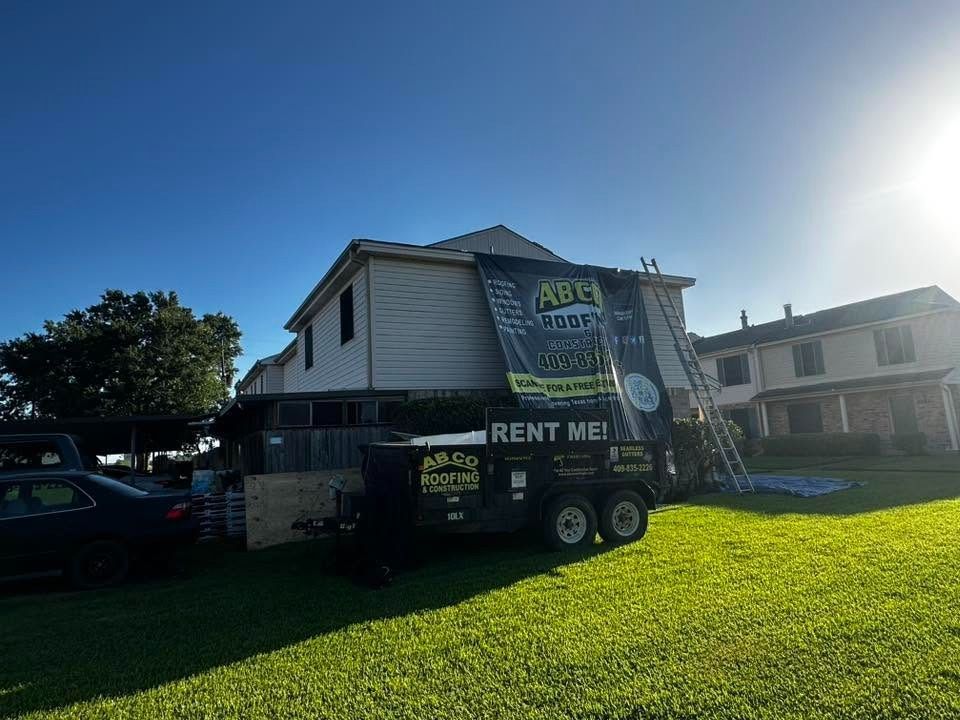 Portable toilet trailer parked on a sunny lawn beside a house, with “RENT ME” signs.