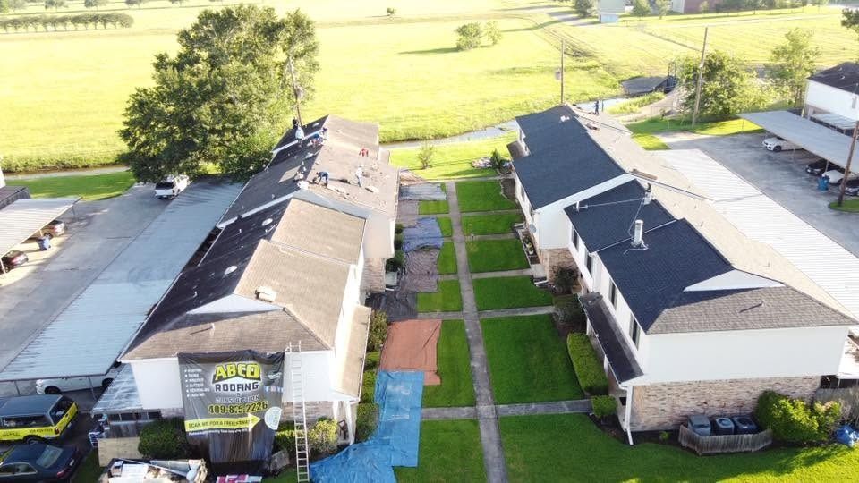 Aerial view of two apartment buildings with a central walkway and green fields beyond