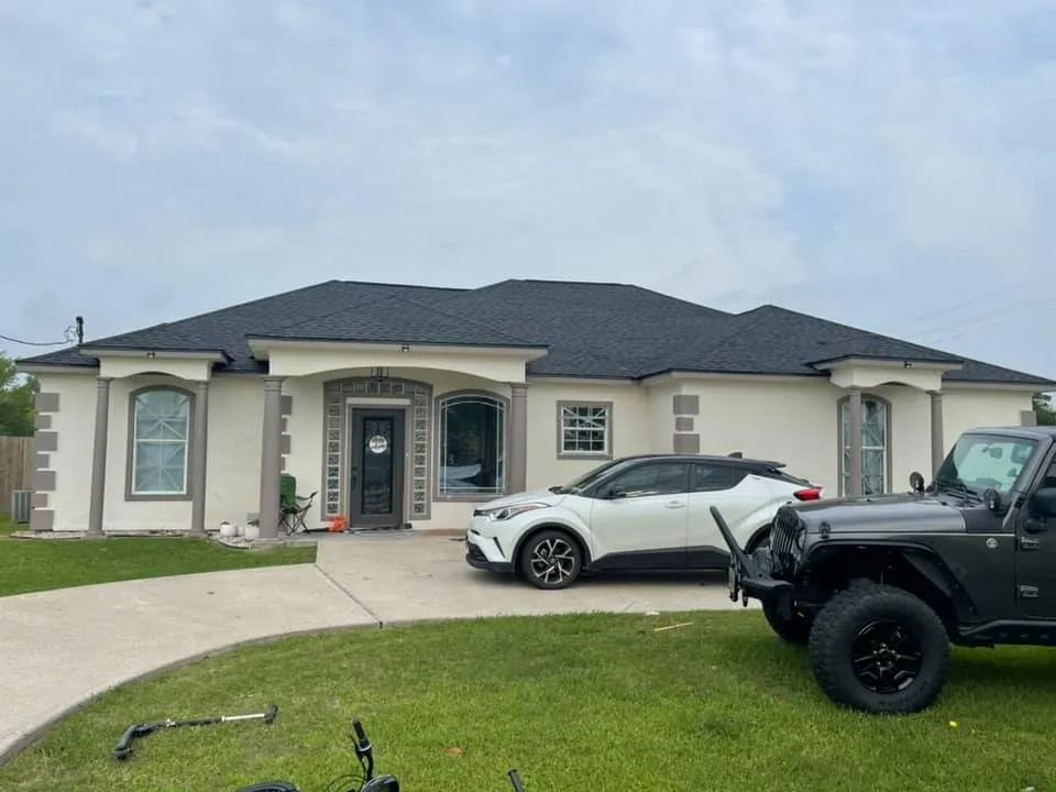 Single-story house with a dark roof, white car in driveway, and black Jeep parked on the right.