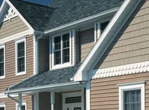 Suburban house exterior with beige siding, dark gray roof, and white-trimmed windows