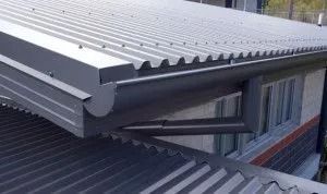 White corrugated metal roof with gutters over a building window and balcony below