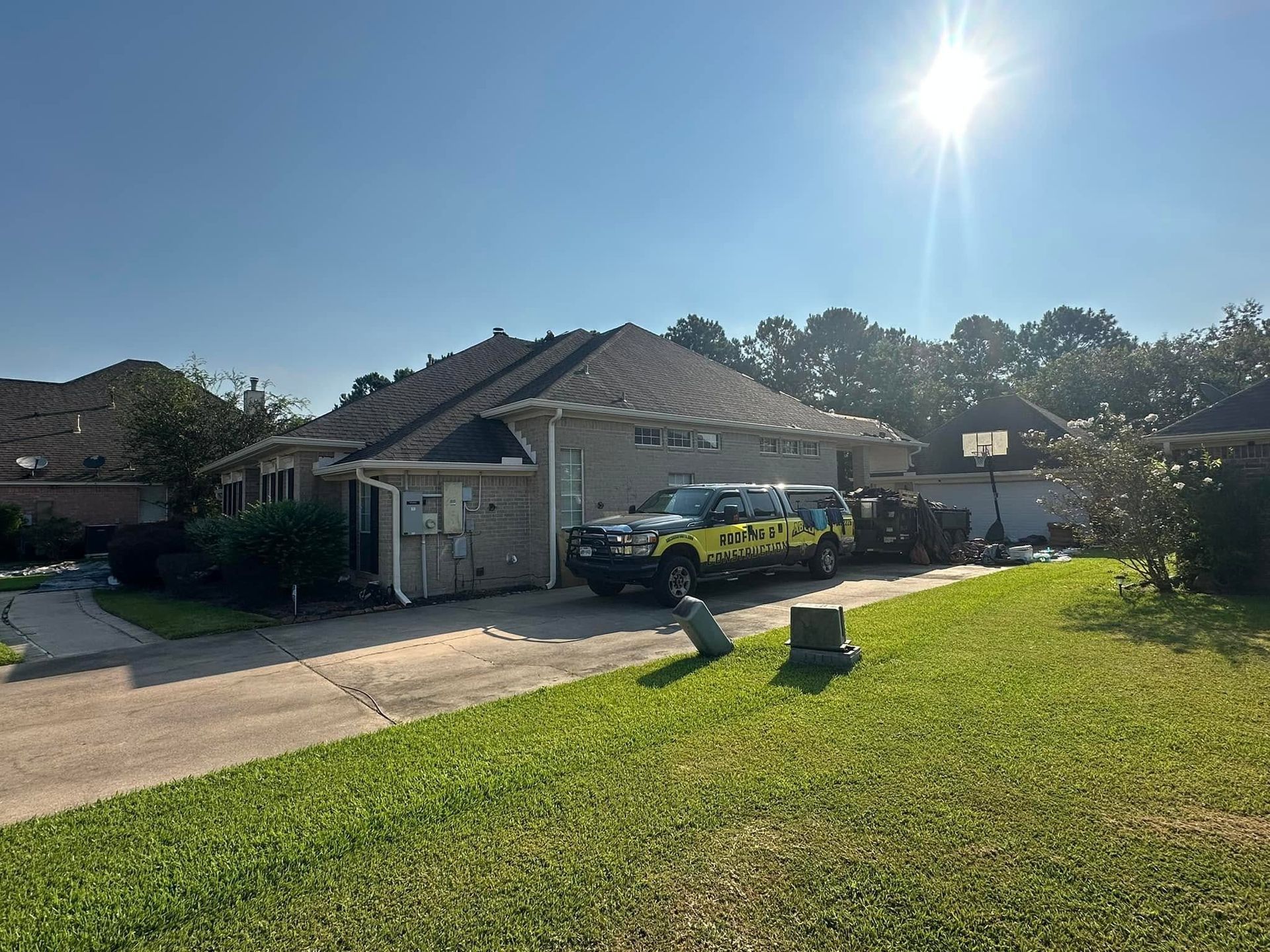 Single-story house with a parked SUV in the driveway and a sunlit front lawn.