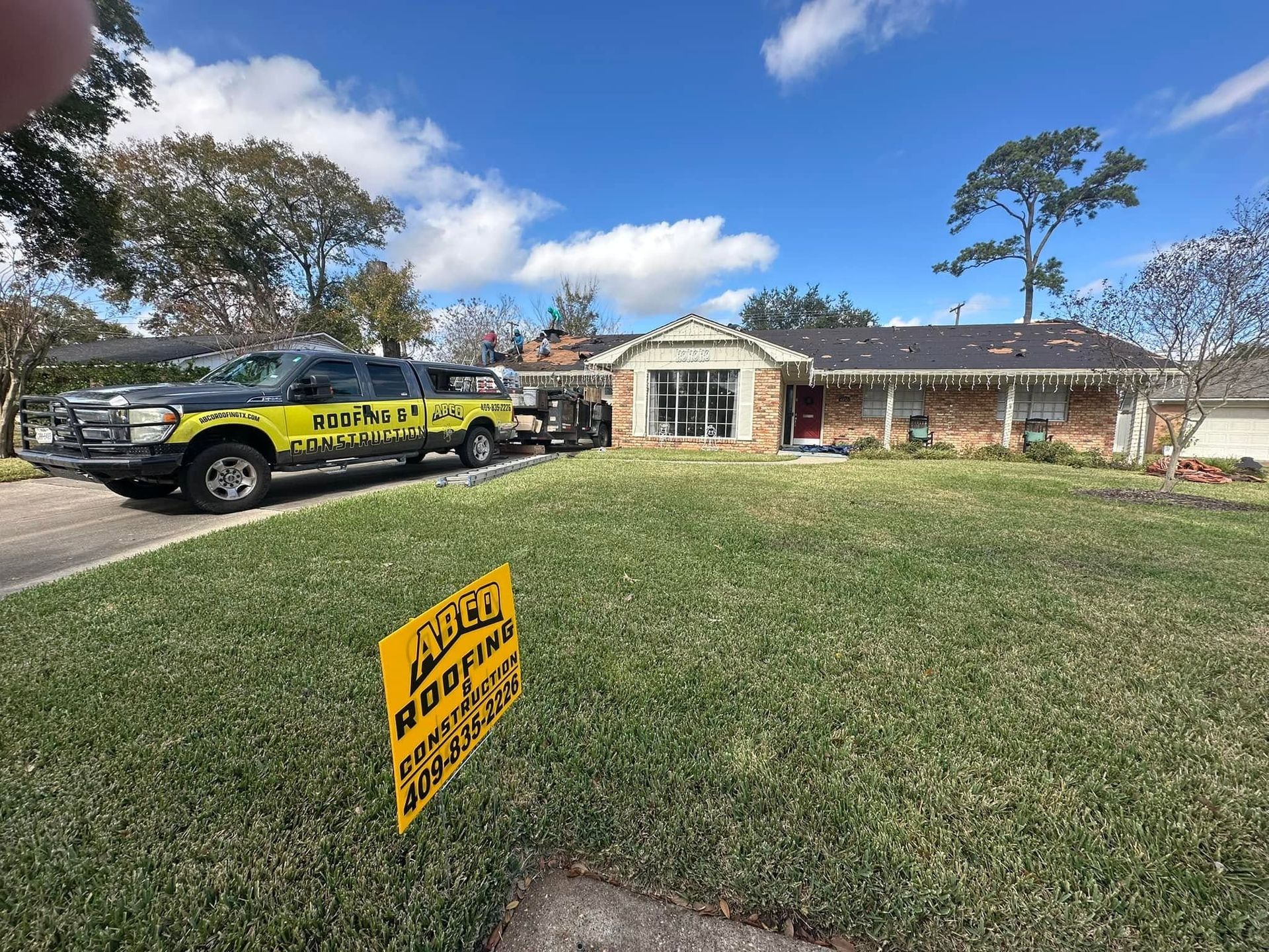Yellow ADT security sign in a front yard with an ADT vehicle parked by a brick house.